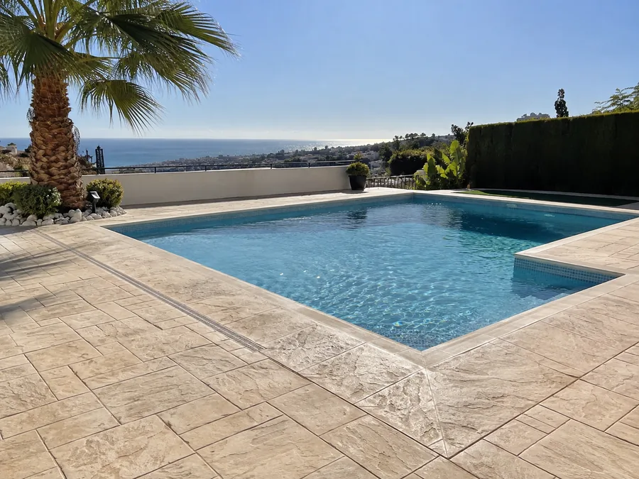 Zona de piscina con hormigón impreso en tono claro en Rincón de la Victoria